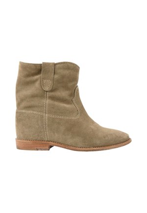 Bottine en daim beige avec un petit talon en bois et une languette, coutures visibles sur les côtés et à l'avant.