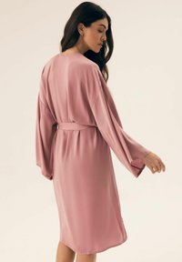 Różowy satynowy szlafrok z szerokimi rękawami, z paskiem w talii i długości do kolan, charakteryzujący się gładką fakturą i prostym wzornictwem.