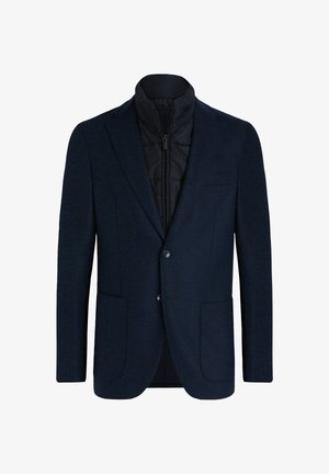 Jūras spēku žakete ar teksturētu vilnas ārpusi, ar augstu apkakli, ar mīkstu iekšējo oderi, divām priekšējām kabatām un pogu aizdari.