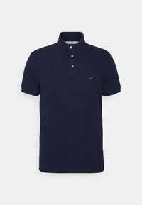 Polo azul marino de algodón, con una tapeta de tres botones, mangas cortas y un pequeño logotipo en el lado izquierdo del pecho.