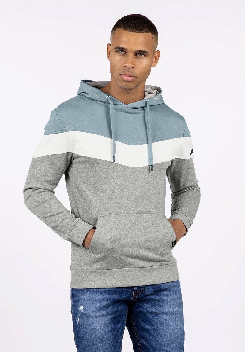 Sudadera con capucha que presenta paneles en azul claro, blanco y gris. Fabricada con un tejido suave, cuenta con un bolsillo frontal y una capucha ajustable con cordón.