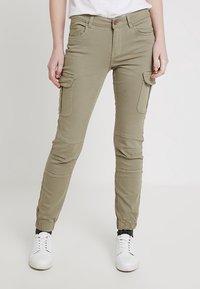 Pantalones cargo verde oliva, de corte ajustado con bolsillos laterales y paneles en las rodillas, fabricados con una tela suave de superficie ligeramente texturizada.