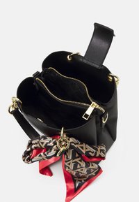 Sac seau noir texturé avec quincaillerie dorée, poche zippée et une écharpe en soie rouge et à motifs attachée. L'intérieur présente un doublure à logo.