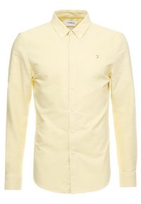 Langärmliges Button-Down-Hemd aus weichem gelben Baumwollstoff. Mit klassischem Kragen, vorderen Knöpfen und einem kleinen gestickten Logo auf der Brust.