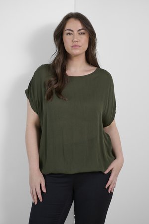 Olive green, short-sleeve top made from soft fabric, featuring a round neckline and relaxed fit, paired with dark blue fitted pants.