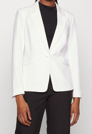 Witte op maat gemaakte blazer met een enkele knoopsluiting, rever met inkeping en voorzakken, gecombineerd met een zwarte coltrui eronder.