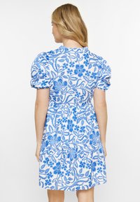 Rochie florală albă și albastră, cu mâneci bufante, talie strânsă și fustă în straturi cu modele florale intricate.