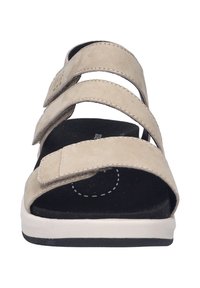 Sandali in suede beige con tre cinturini regolabili, una soletta nera texturizzata e una suola in gomma bianca, progettati per comfort e facilità di utilizzo.