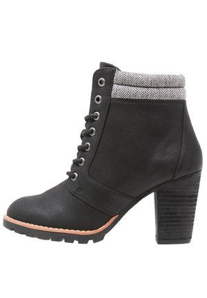 Bottines noires en cuir avec un talon épais, un revers en chevron gris, un bout rond et un système de laçage à l'avant avec des œillets en métal.