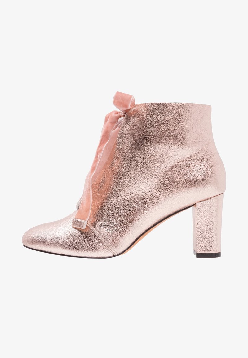 Stivale alla caviglia in oro rosa con finitura metallica, punta affusolata, dettaglio a fiocco nella parte anteriore e tacco grosso. Texture liscia e design elegante.