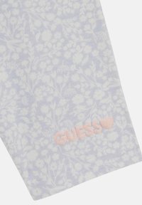 Leggings a fantasia in lavanda chiaro con design floreale bianco. Presentano un logo "GUESS" rosa all'orlo. Tessuto morbido e elasticizzato.