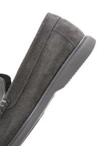 Chaussure slip-on en daim gris avec une surface texturée et une semelle en caoutchouc. Présente des surpiqûres sur les côtés et un design à profil bas.