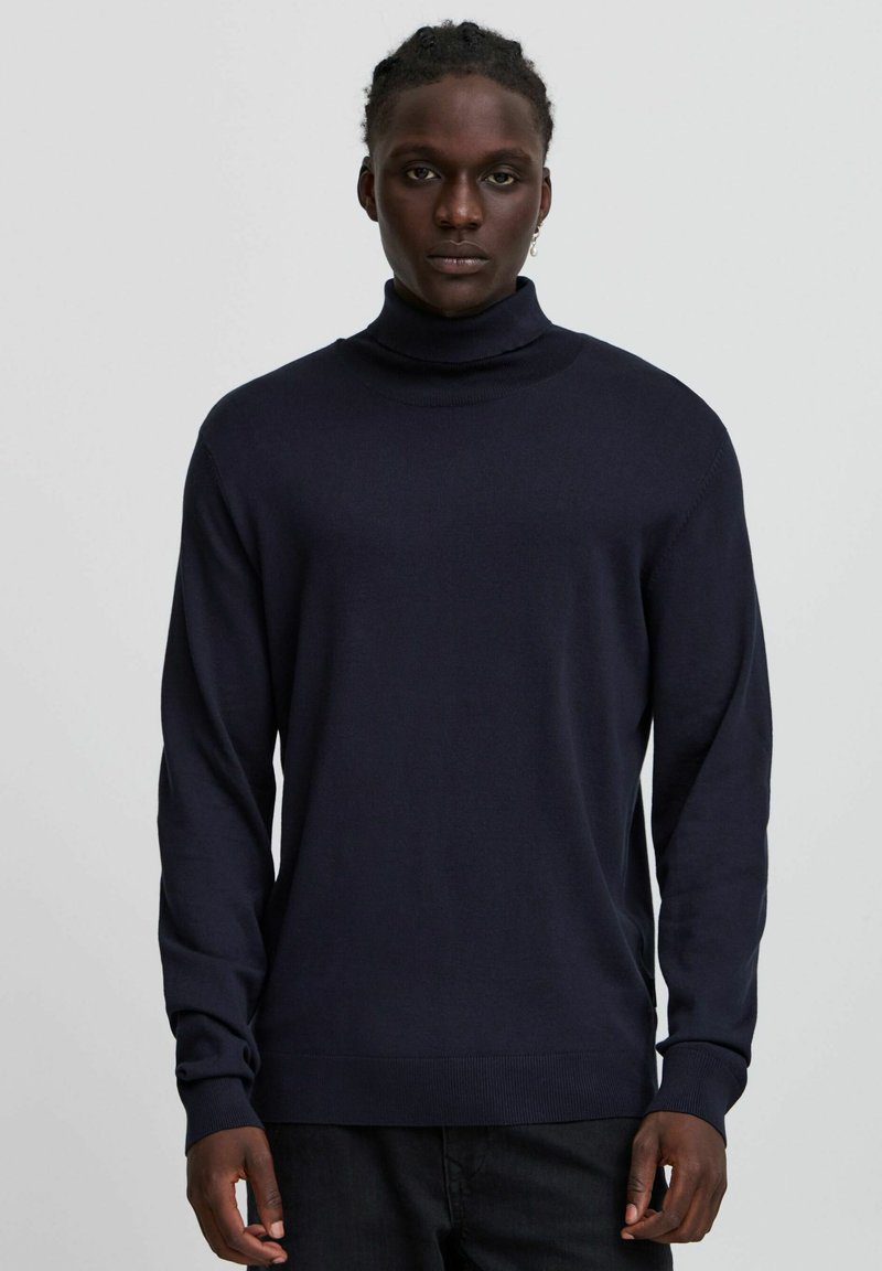 Maglione a collo alto blu navy in tessuto a maglia con maniche lunghe e vita aderente, caratterizzato da una texture liscia e un design minimale.