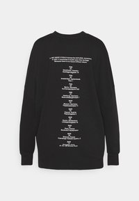 Sudadera negra de manga larga, con texto impreso en blanco que enumera lugares y fechas, cuello redondo y corte relajado.