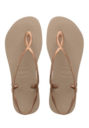 Infradito in gomma marrone con suole testurizzate. Le cinghie presentano un design intrecciato e un dettaglio ad anello all'alluce, offrendo uno stile minimalista.