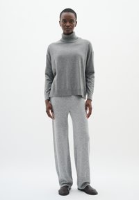 Gray, knitted turtleneck sweater with a loose fit and ribbed hem, paired with matching wide-leg gray pants, both made of soft fabric.