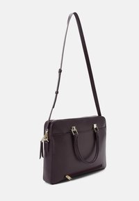 Lilla læderhandtaske med justerbar skulderrem, dobbelte håndtag, guldfarvet hardware og en lynlåslomme bagpå.