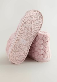 Lyserøde, bløde hjemmesko med en tekstureret overflade og et puffet mønster. Gummisålen har et stjernemønster og er mærket med størrelse 6.