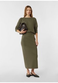 Olive zielony dzianinowy sweter i dopasowana długa spódnica o luźnym kroju. Całość dopełnia czarna skórzana torebka oraz szpiczaste baleriny.