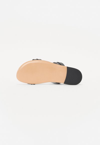 Sandalia negra con correas de cuero liso y una suela de goma de color bronceado claro. Presenta un tacón decorativo y una parte inferior texturizada para un mejor agarre.