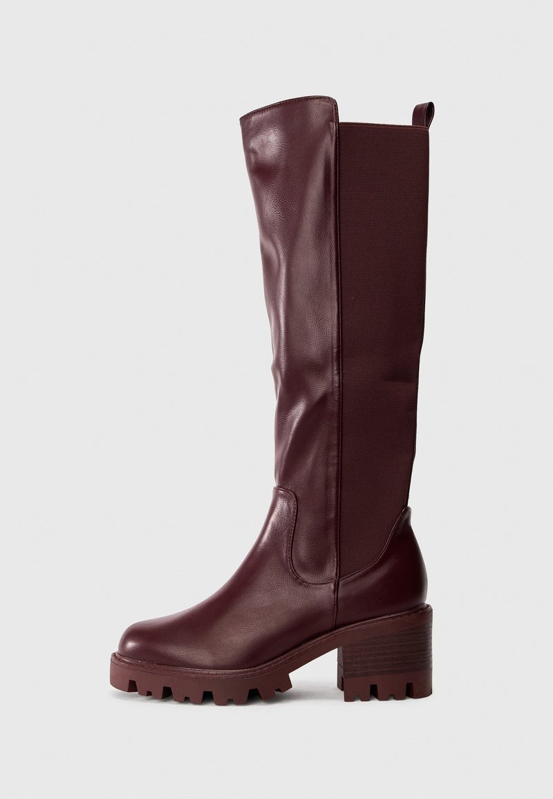 Vīnkrāsas ceļgala augstuma zābaki ar gludu ādu un elastīgu audumu, biezā papēža un teksturētu zoli, kas nodrošina labāku saķeri.