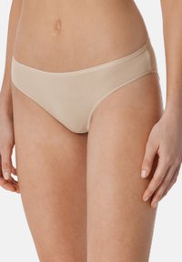 Beige bikini slips van ribbelstof, met een lage taille en naadloze randen voor comfort. Gladde textuur en eenvoudige details.