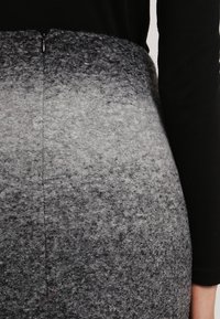 Grå filt kjol med en ombre-effekt som övergår från ljusgrå till mörkgrå, med en enkel dragkedjestängning bak.