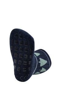 Marineblaue Socken mit rutschfester Textursohle, die mit grünen Baum-Mustern und einem gerippten Bündchen versehen sind. Das Material scheint weich und dehnbar zu sein.
