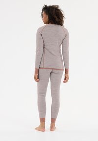 Grijze lange mouwtop en bijpassende legging met een gestructureerd patroon, met roze accenten bij de manchetten en zoom. Uitzicht van achteren.