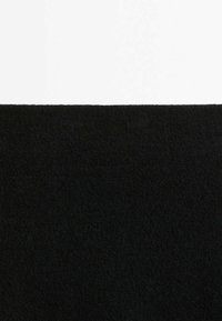 Carré de tissu noir texturé centré sur un fond blanc, montrant le contraste entre les deux surfaces.