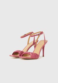 Ροζ πέδιλα με ψηλό τακούνι, σχέδιο με στριφογυριστή λεπτομέρεια στο μπροστινό μέρος και λεπτό λουράκι στον αστράγαλο, με ομαλή υφή δέρματος και μυτερό τακούνι.