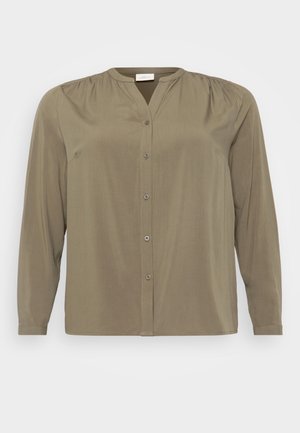 Blusa verde oliva realizzata in tessuto morbido, con una chiusura frontale a bottoni, colletto a bande e dettagli arricciati sulle spalle. Maniche lunghe.