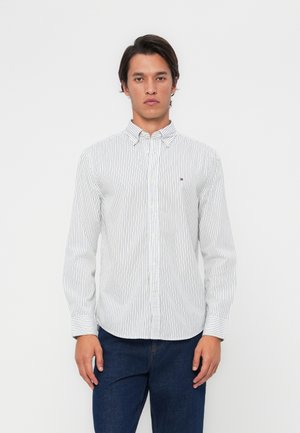 White long-sleeve shirt with navy vertical stripes, button-down collar, and small logo on the left chest. Soft, lightweight fabric.
