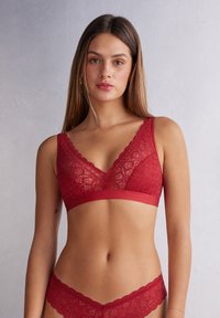 Rode kant beha met een golvende rand en een stevige band. Heeft driehoekige cups en een bloemmotief. Gecombineerd met een bijpassende kanten slip.