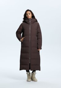 Brun pufferjakke med høj krave, lynlåslukning, sidelommer og en lang, lige silhuet. Teksturert, quiltet design.