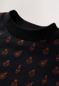 Felpa nera con scollo a coste e motivo integrale di ornamenti arancioni, comprendenti diverse forme e disegni.