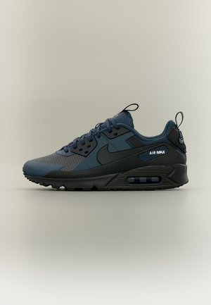 Тъмносиньо и черно маратонка Nike Air Max с видима въздушна възглавница и дръжки на езика и петата, показани отстрани на неутрален фон.