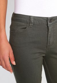 Olivgrön denimbyxor med slim fit, med framfickor, knäppning med översta knapp och diskreta sömnadsdetaljer.