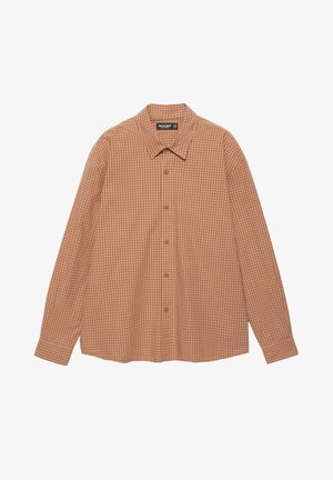 Chemise à carreaux beige à boutons portée sur un T-shirt blanc, associée à un pantalon en denim foncé ample et des chaussures compensées marron. Textures lisses et coupe décontractée.