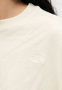 Μπεζ βαμβακερό T-shirt με ριμπ λαιμόκοψη και μικρό ανάγλυφο λογότυπο στο στήθος. Μαλακή υφή και άνετη εφαρμογή.