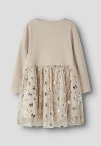 Robe à manches longues avec un corsage beige texturé et une jupe en tulle à plusieurs couches ornée de motifs de nœuds argentés et de sequins épars.