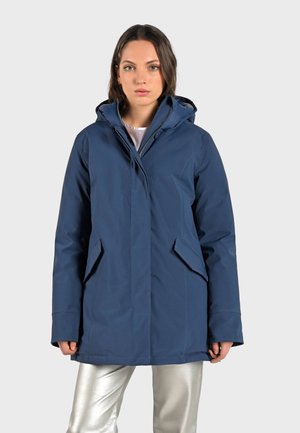 Marine blauwe pufferjack met een capuchon, zijzakken en een ritssluiting aan de voorkant, gemaakt van soepel, waterafstotend materiaal, ontworpen voor warmte.