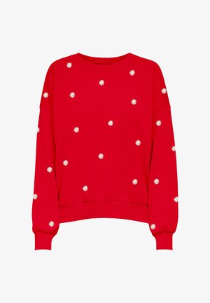 Punane pusa pikkade varrukatega, valgete lillemustritega, mis on laiali tikitud kanga peale. Lõdvestunud lõige ja soonikkoes mansetid.