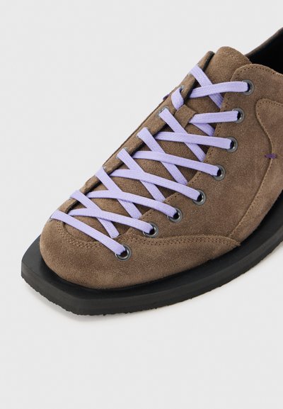 Καφέ παπούτσι από σουέτ με ανοιχτό μοβ κορδόνια που διασταυρώνονται μέσα από μαύρα ρουθούνια σε μαύρη λαστιχένια σόλα.