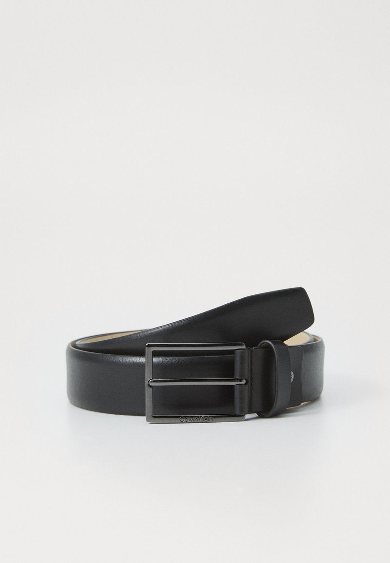 Cinturón de cuero negro con una textura suave, que cuenta con una hebilla de metal rectangular y un logo sutil. Los extremos se van afinando para un aspecto refinado.