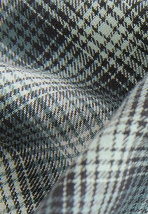 Tkany materiał w wzór houndstooth w odcieniach czerni, bieli i jasnoniebieskiego, o teksturowanej powierzchni i gładkim układzie.