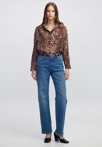 Blouse met luipaardprint en een kraag, gecombineerd met rechte blauwe spijkerbroek en zwarte blokkheels.