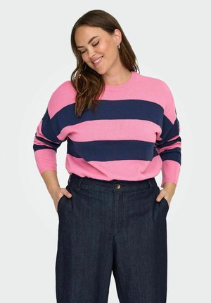 Maglione a righe rosa e blu navy con maniche lunghe e scollatura tonda, abbinato a pantaloni in denim scuro con chiusura a bottoni.