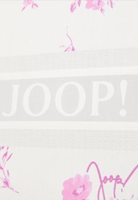 Tessuto bianco con motivi floreali rosa e la scritta "JOOP!" in grandi lettere grasse, accompagnato da una sottile fascia grigia testurizzata.