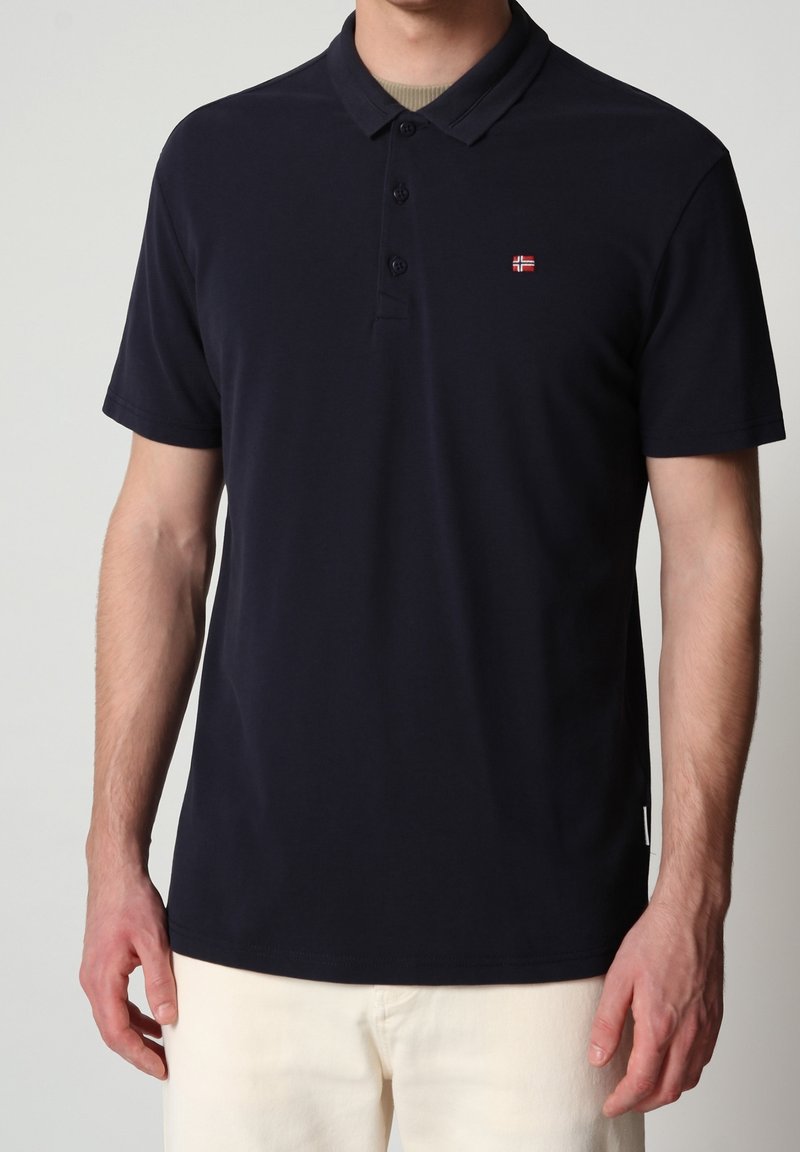 Polo bleu marine avec un col classique, une patte de boutonnage à trois boutons, des manches courtes, et un petit logo brodé sur le côté gauche de la poitrine.